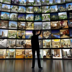 silhouette of a man standing in front of a bank of screens of media