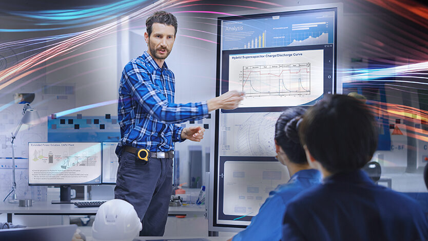 Engineers discussing hybrid supercapacitors and looking at data on an easel