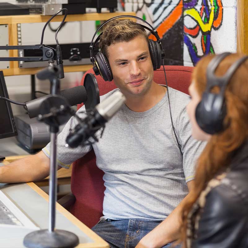 man and woman with headphones talking live during radio broadcast