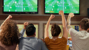 sports bar customers watching multiple TVs with the same content on them