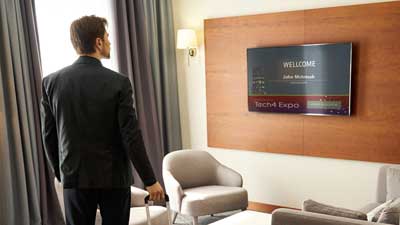 Man standing in hotel looking at welcome message on the TV