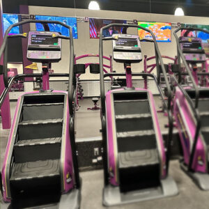 gym facility with tvs on wall in front of treadmills