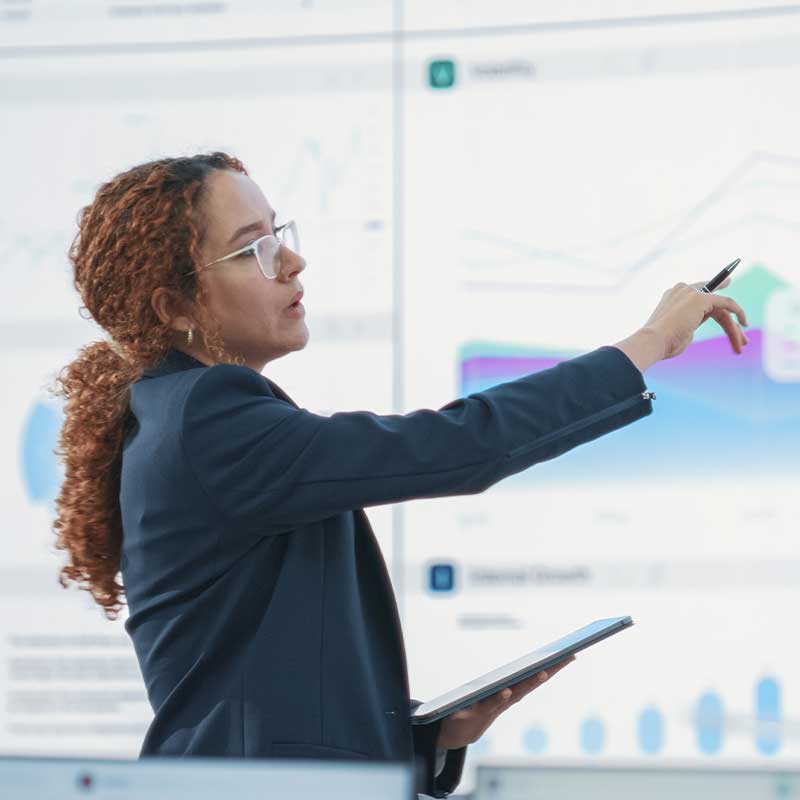 woman pointing to peak charts on a large screen