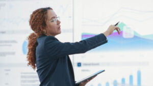 woman pointing to peak charts on a large screen